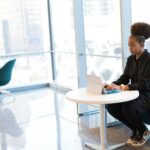 woman sits of sofa while using tablet computer
